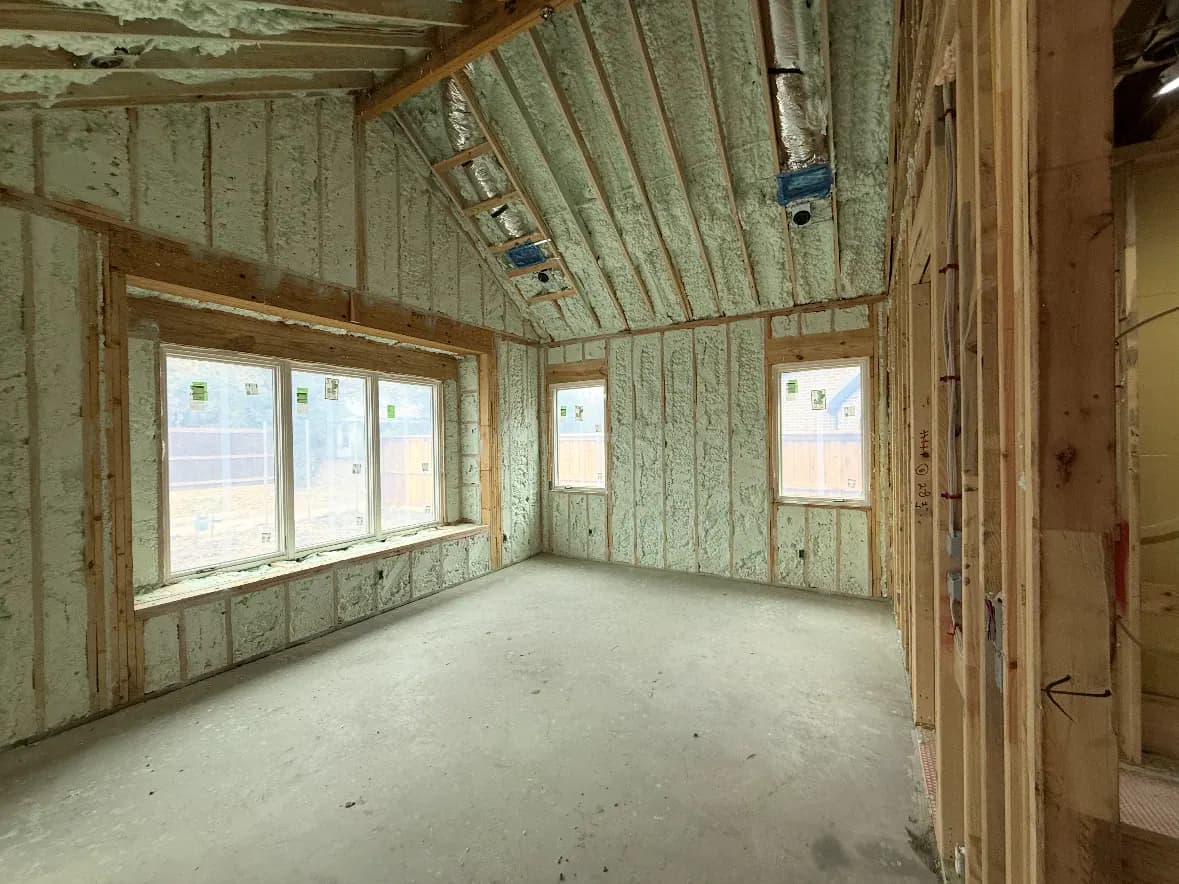 Vaulted new-construction room with spray foam across walls and roofline